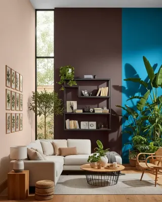 Living room with blush, deep brown and bright blue color-blocked walls, cream sectional sofa and large tropical plants